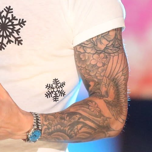 Adam Levine's floral and bird designs on a tattooed forearm