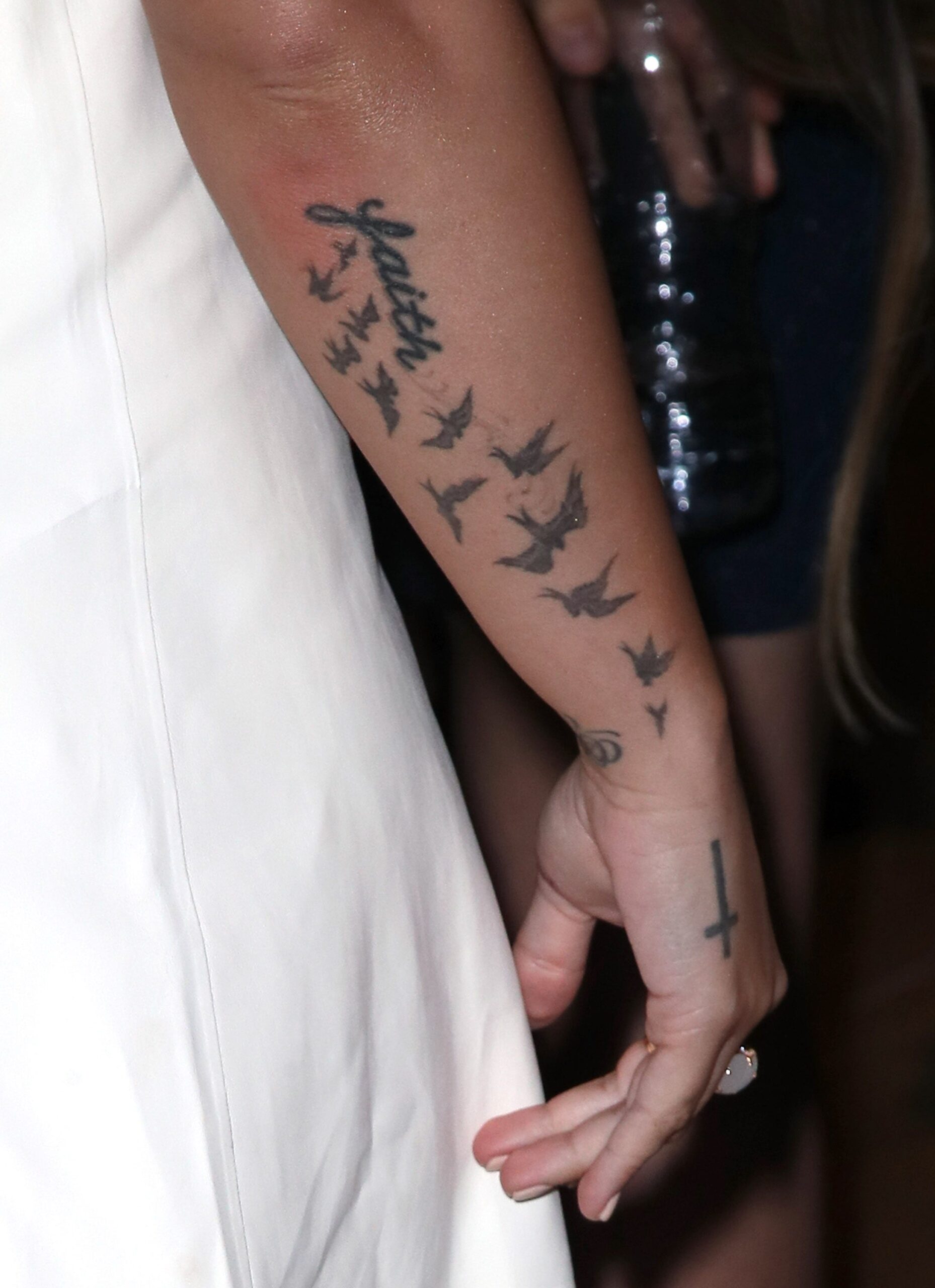 Demi Lovato’s twelve bird forearm tattoo and the cross near her wrist