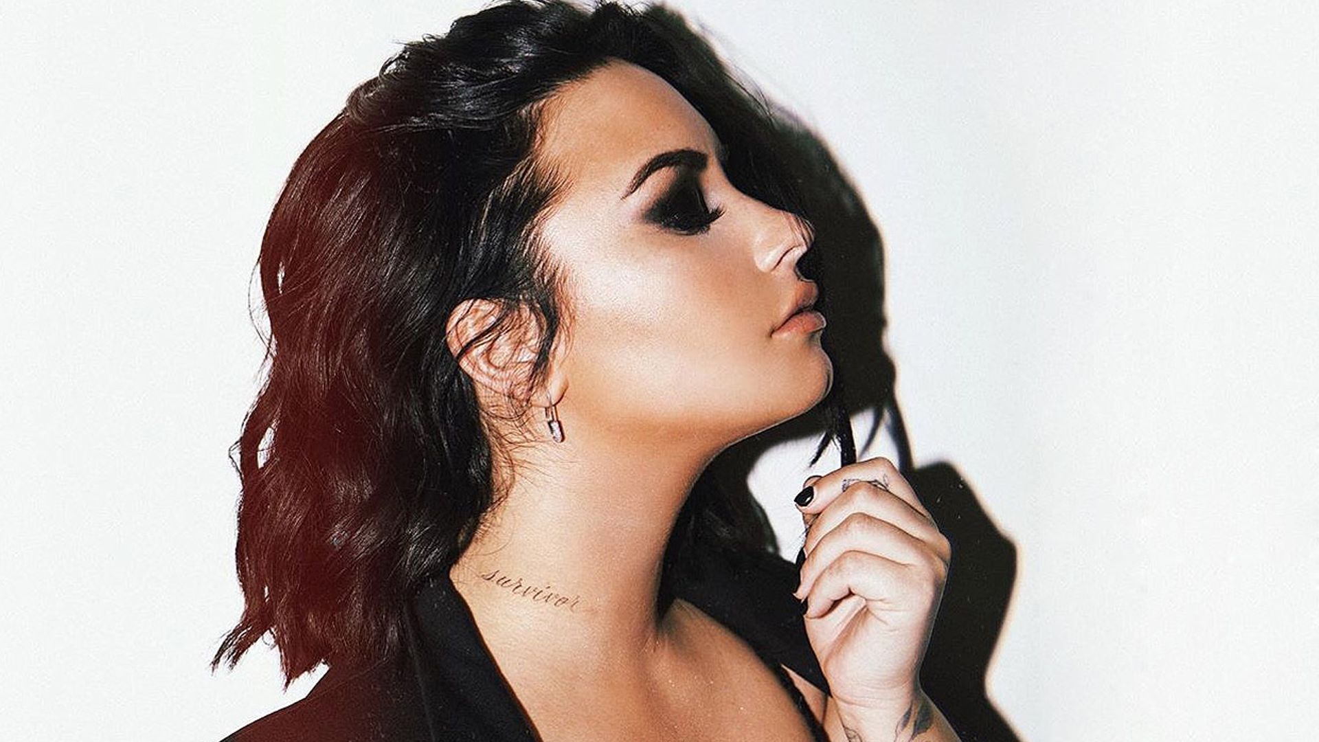 Demi Lovato’s cursive Survivor tattoo on the side of her neck
