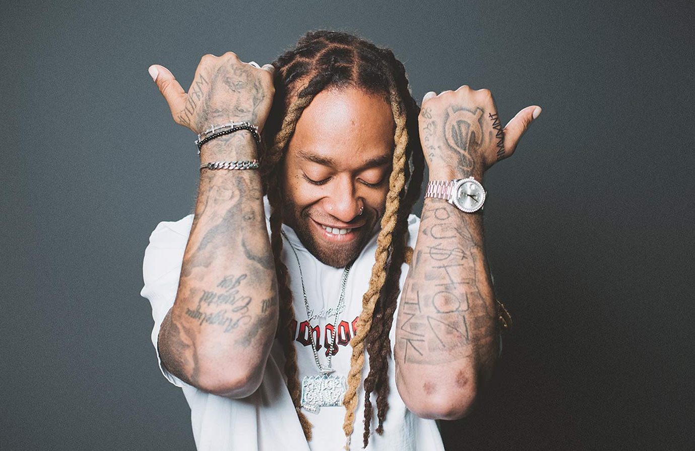 Ty Dolla $ign raises both arms, showing distinct forearm and hand tattoos
