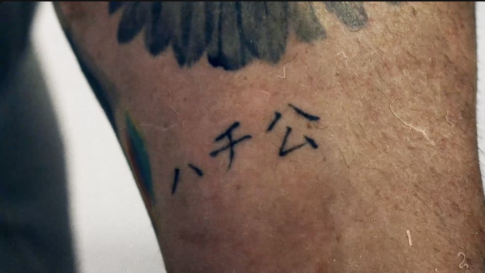 Alan Ritchson’s forearm lettering and cross tattoos shown during GQ Tattoo Tour.