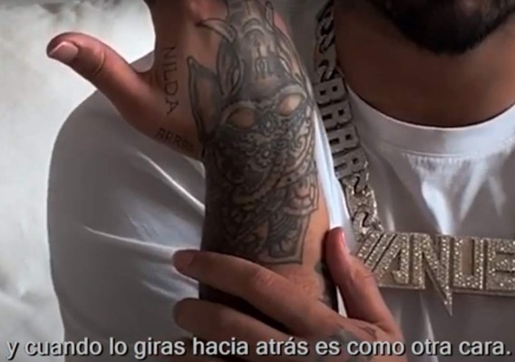 Anuel AA showing the elephant tattoo on his hand