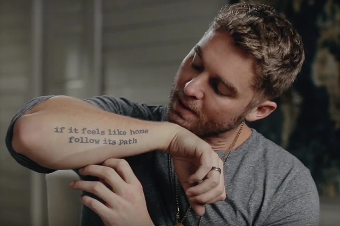 Brett Young forearm tattoo reading if it feels like home follow its path