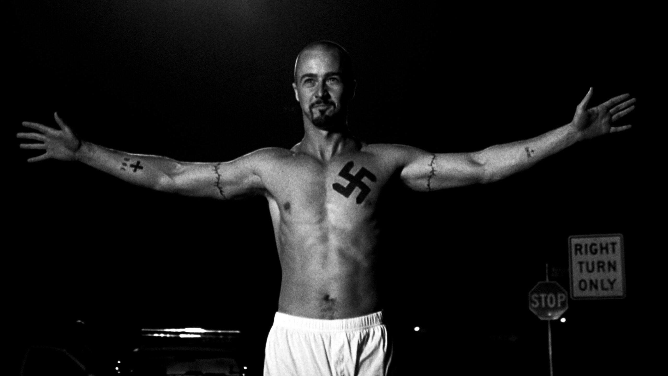 Edward Norton as Derek Vinyard showing the American History X chest and arm tattoos