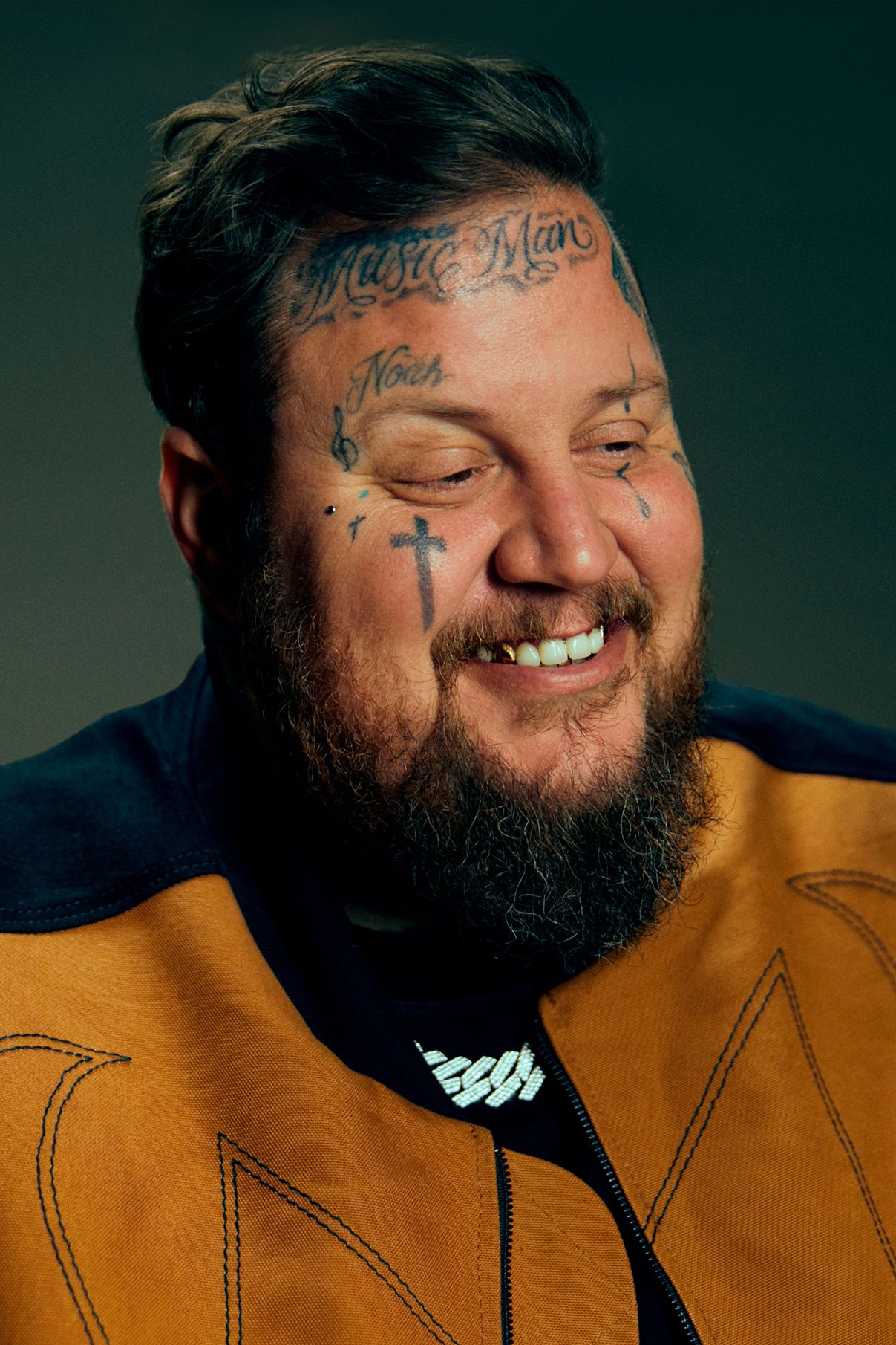Close portrait showing Jelly Roll’s forehead lettering, cheek cross and smaller face tattoos