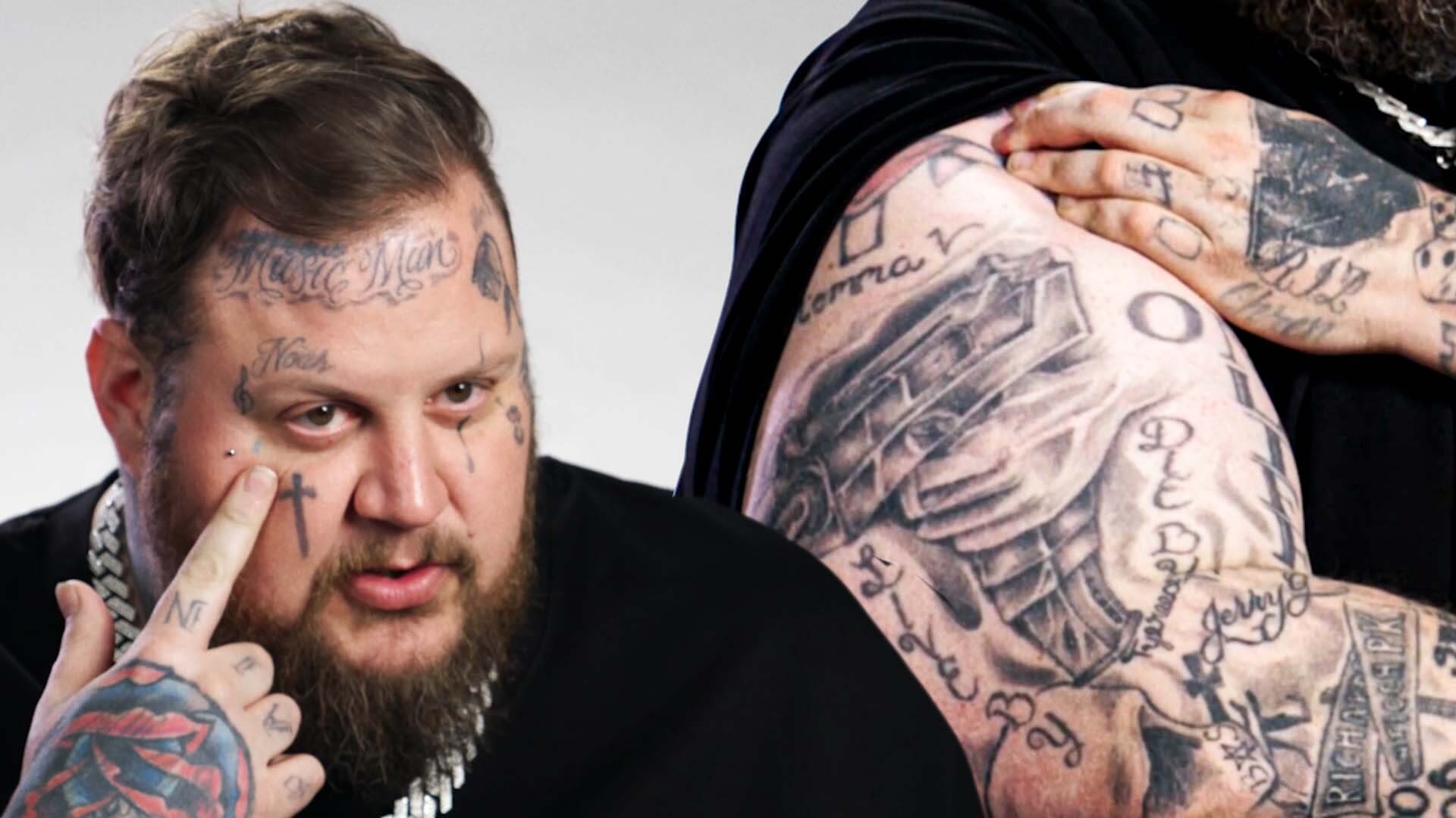 Jelly Roll showing the tattoos across his face, hands and upper arm during a tattoo tour