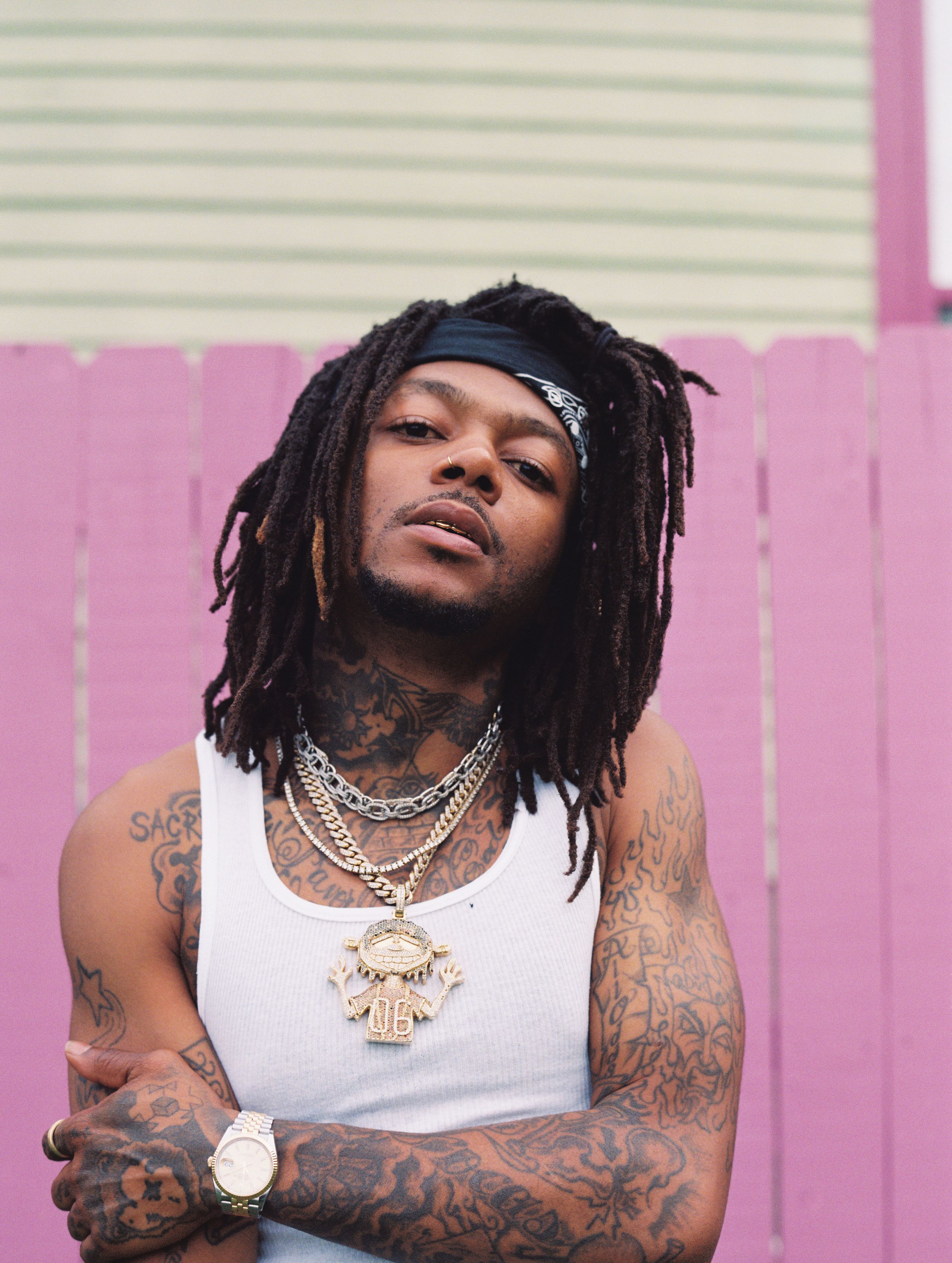 J.I.D showing the dense tattoo work across his chest, arms and stomach