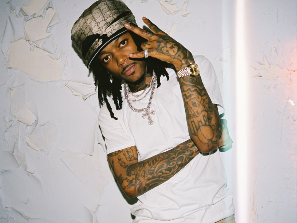J.I.D with the tattooed arms and hands visible in a portrait