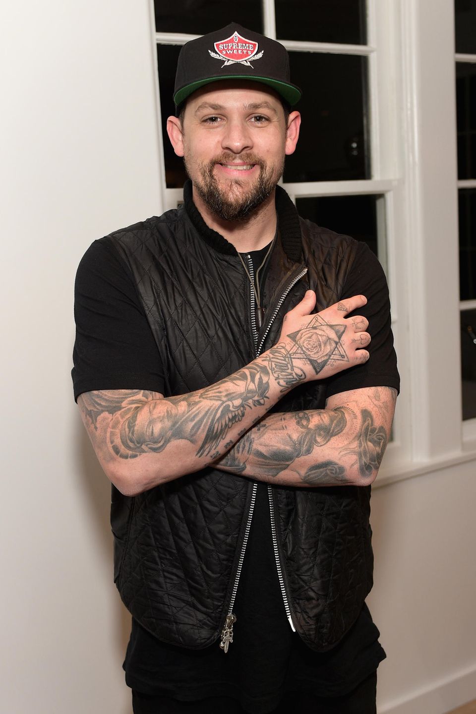 Joel Madden crossed arms tattoos showing floral and geometric ink