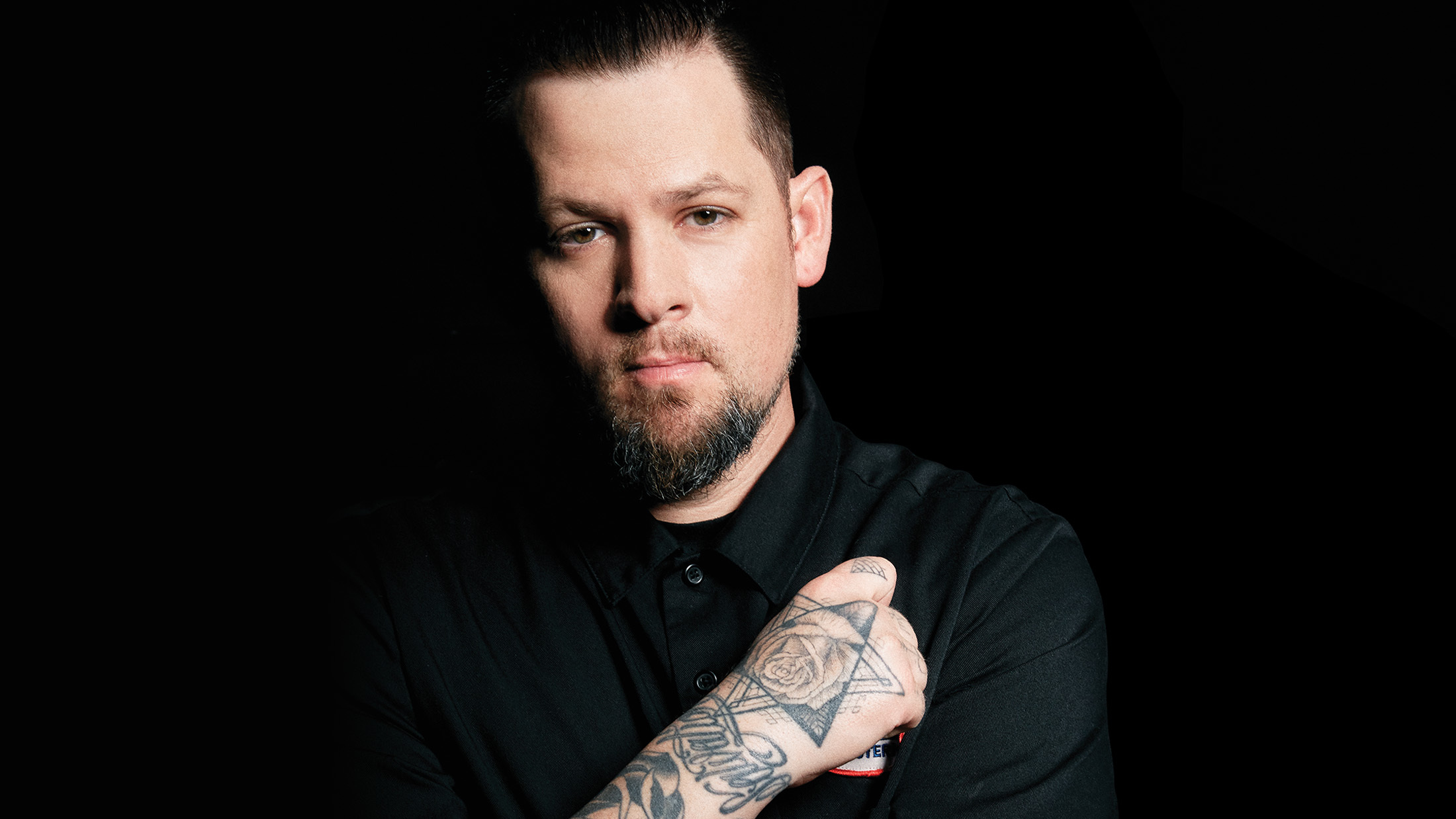 Joel Madden tattoos on his forearm and hand in a close portrait