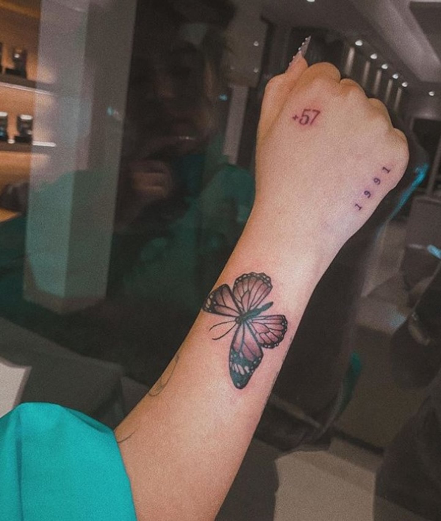 Close-up of Karol G’s butterfly, 1991 and +57 tattoos