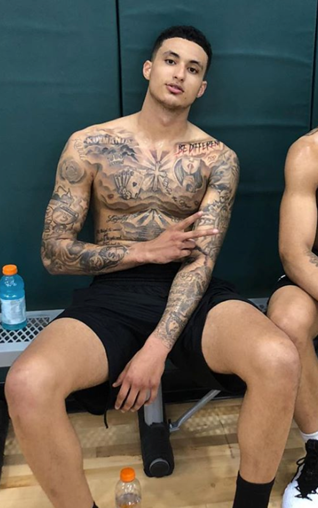 Kyle Kuzma praying hands and Ginny chest tattoos in a high-quality seated portrait