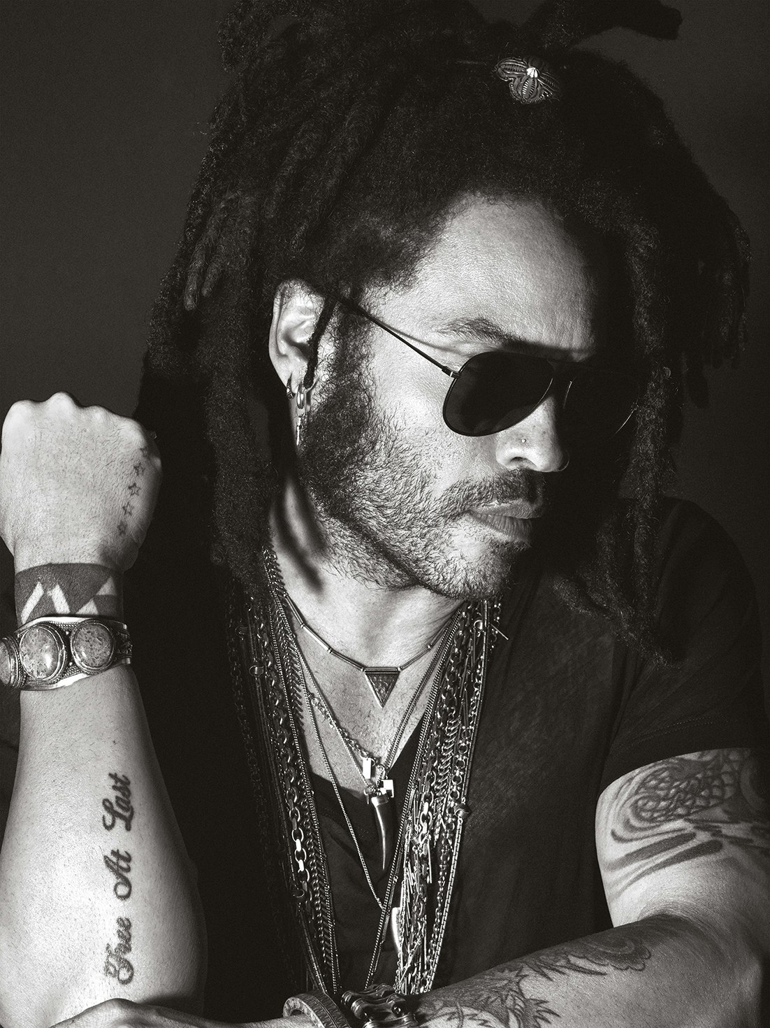 Lenny Kravitz portrait clearly showing the Free at Last lettering tattoo on his forearm