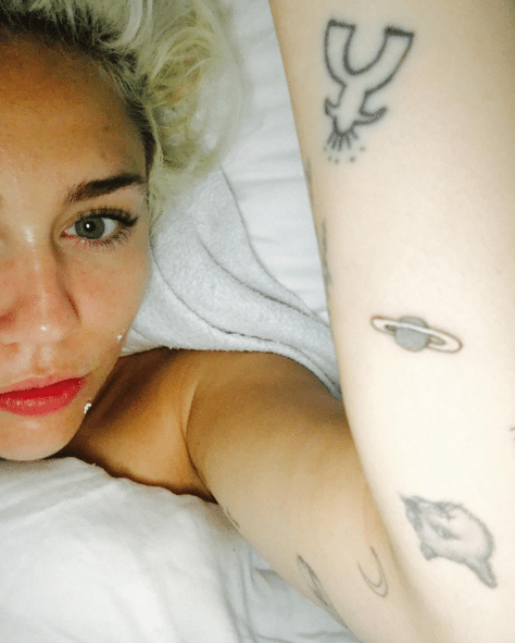 Miley Cyrus showing the planetary arm tattoo