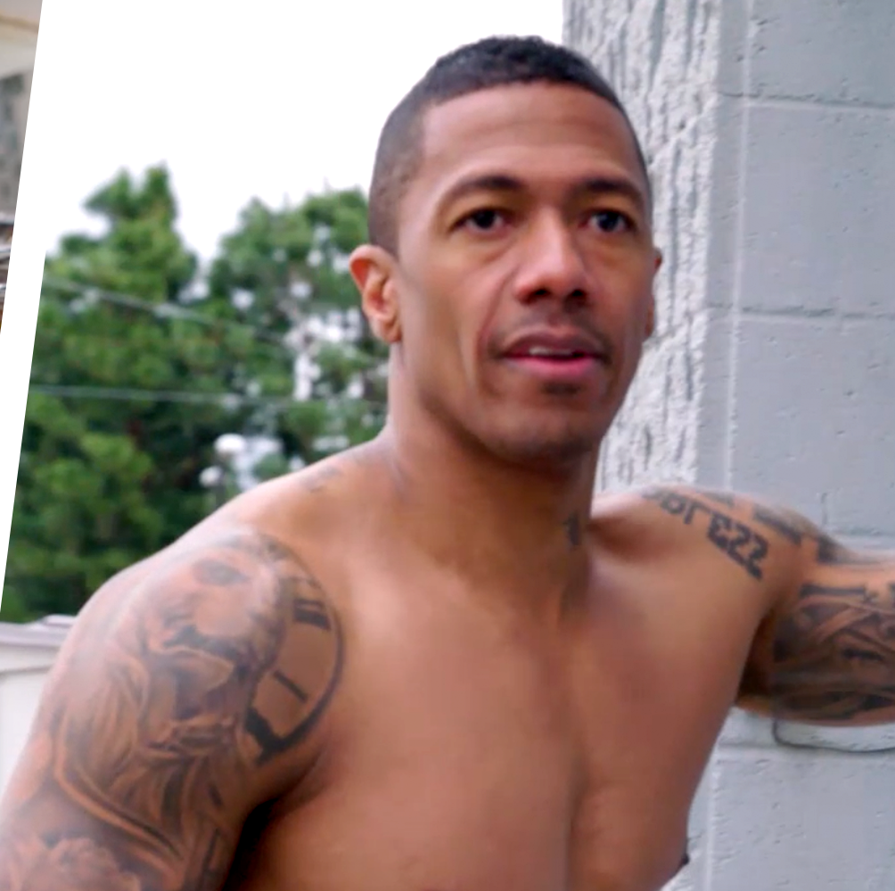 Nick Cannon shirtless portrait showing clock and lion tattoos across the shoulder and arm