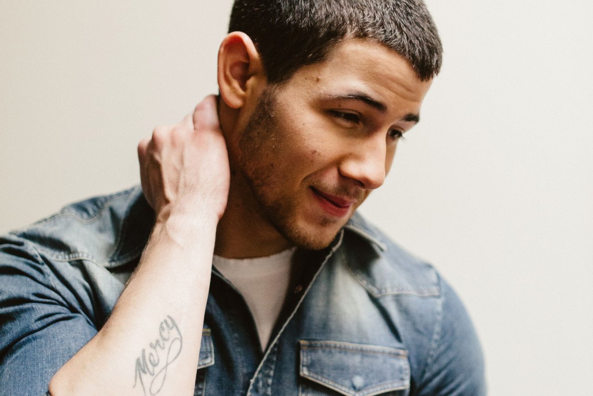 Nick Jonas showing forearm tattoo symbols