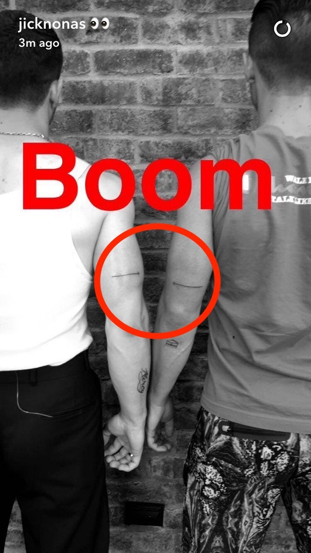 Nick and Joe Jonas showing their matching horizontal arrow tattoos on the backs of their upper arms