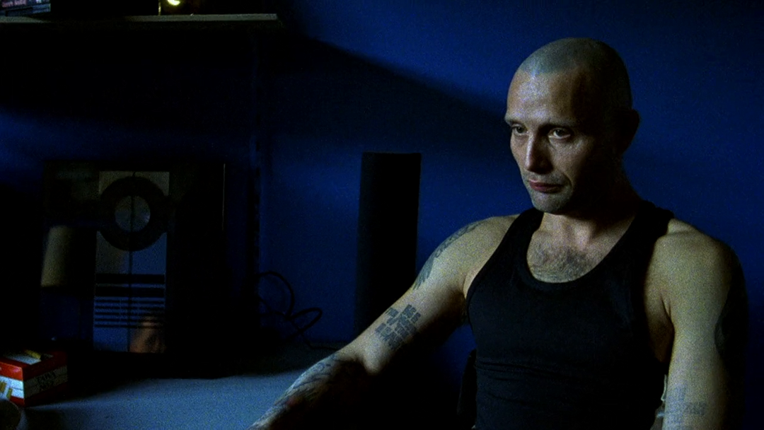 Mads Mikkelsen as Tonny in a close portrait with visible shoulder and arm tattoos