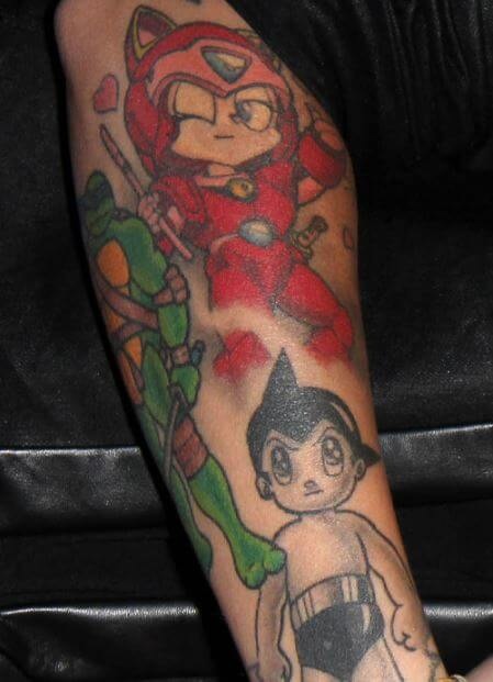 Ruby Rose cartoon figures on her forearm, including a bright red character and a small black-and-white figure