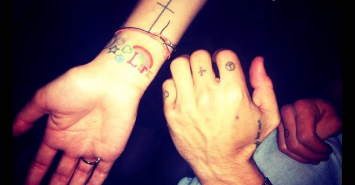 Ruby Rose hand and wrist tattoos showing the cross, small symbols and rainbow lettering