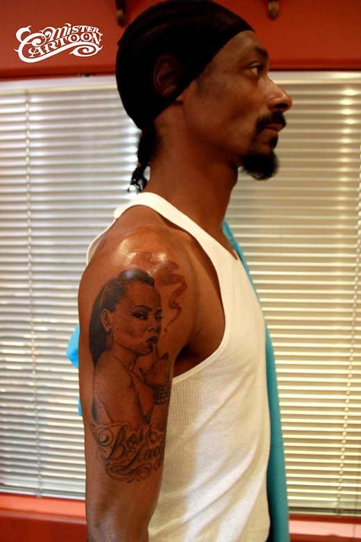 Snoop Dogg showing the flowing woman portrait tattoo on his upper arm