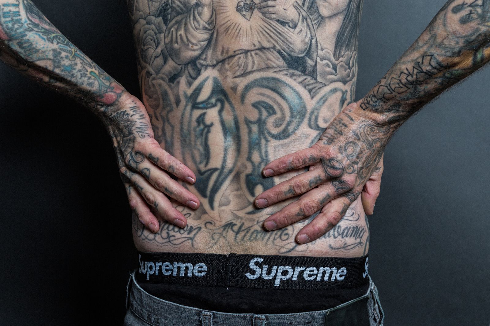 Travis Barker’s large back tattoo with family portraits, religious imagery and lettering