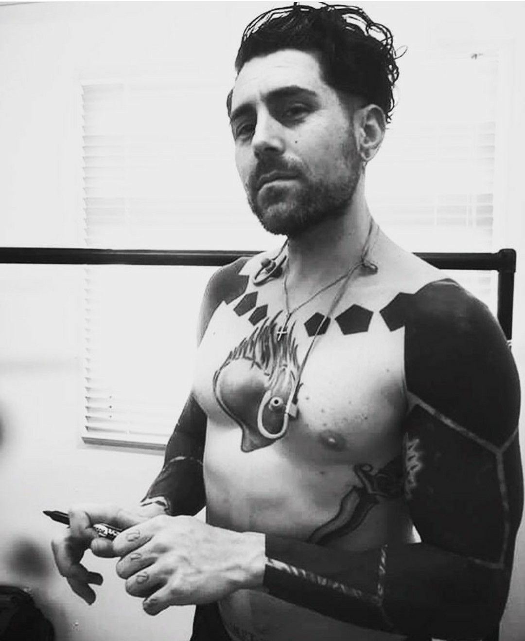 Davey Havok tattoos: shirtless black-and-white portrait showing the anatomical heart chest tattoo and bold dark arm coverage