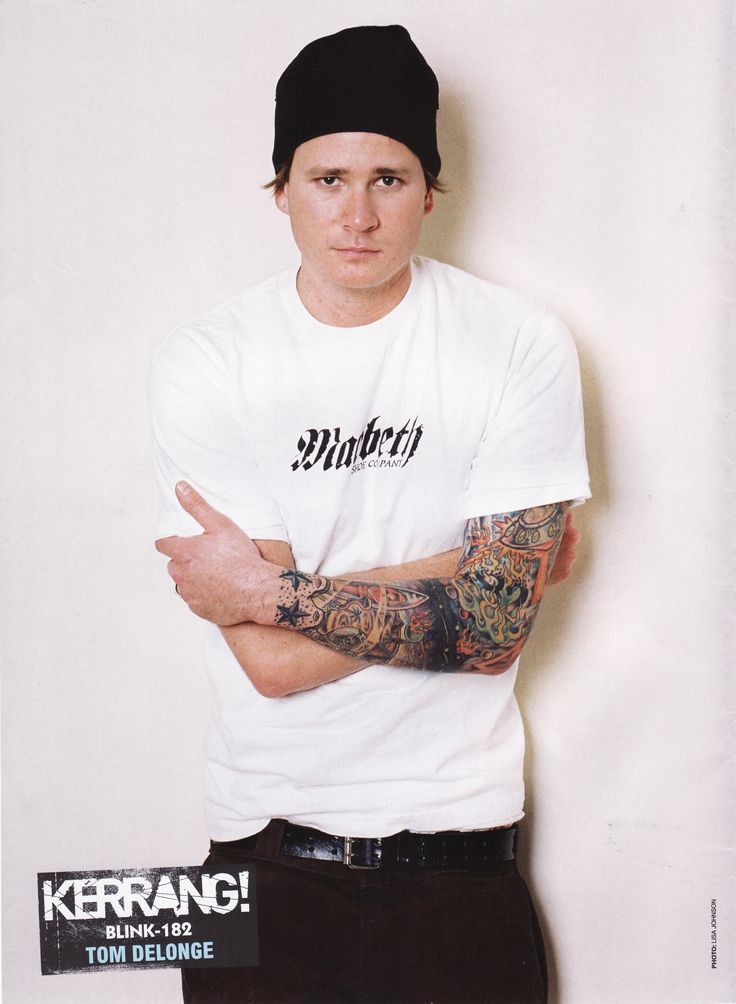 Tom DeLonge tattoos: early Blink-182 promotional portrait showing the full right-arm sleeve, stars and saturated color blocks