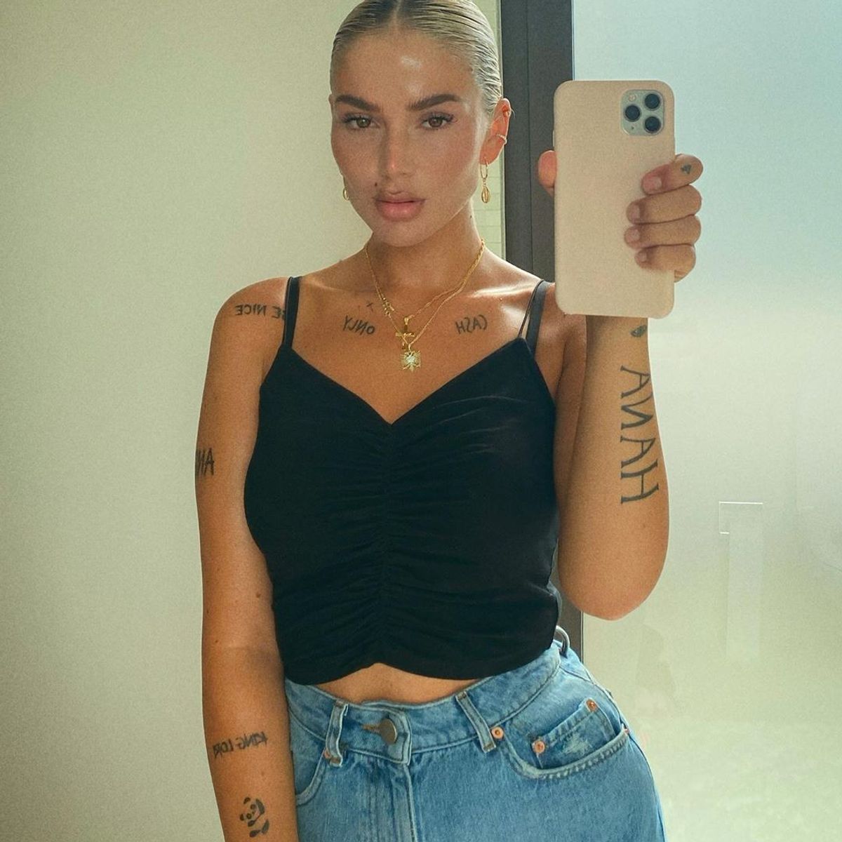 Loredana tattoos: clear mirror portrait showing CASH ONLY across the collarbone, HANA on the arm and large vertical lettering on the opposite arm