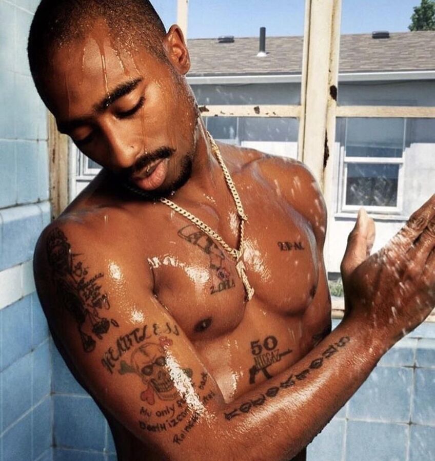 Tupac Shakur tattoos: clear shower portrait showing chest marks, the Nefertiti piece, the Heartless skull and arm lettering