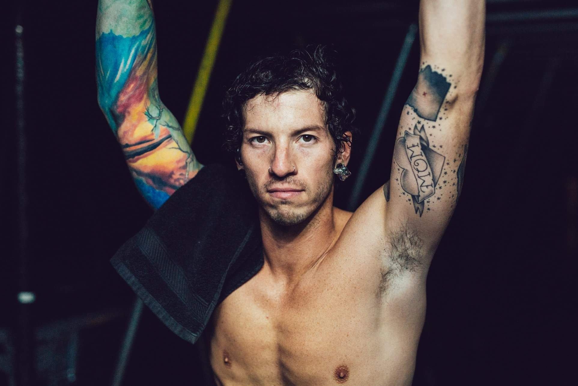 Josh Dun tattoos: high-resolution portrait with both arms raised and the colourful sleeve fully exposed