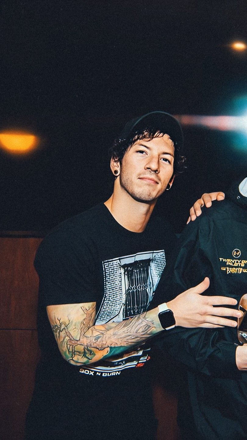 Josh Dun tattoos: portrait showing the tree and root work wrapping across the forearm