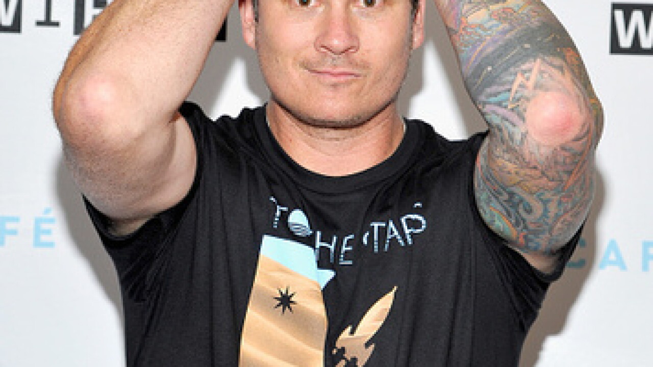 Tom DeLonge tattoos: close event photograph showing the raised arms, colored sleeve and wrist details clearly