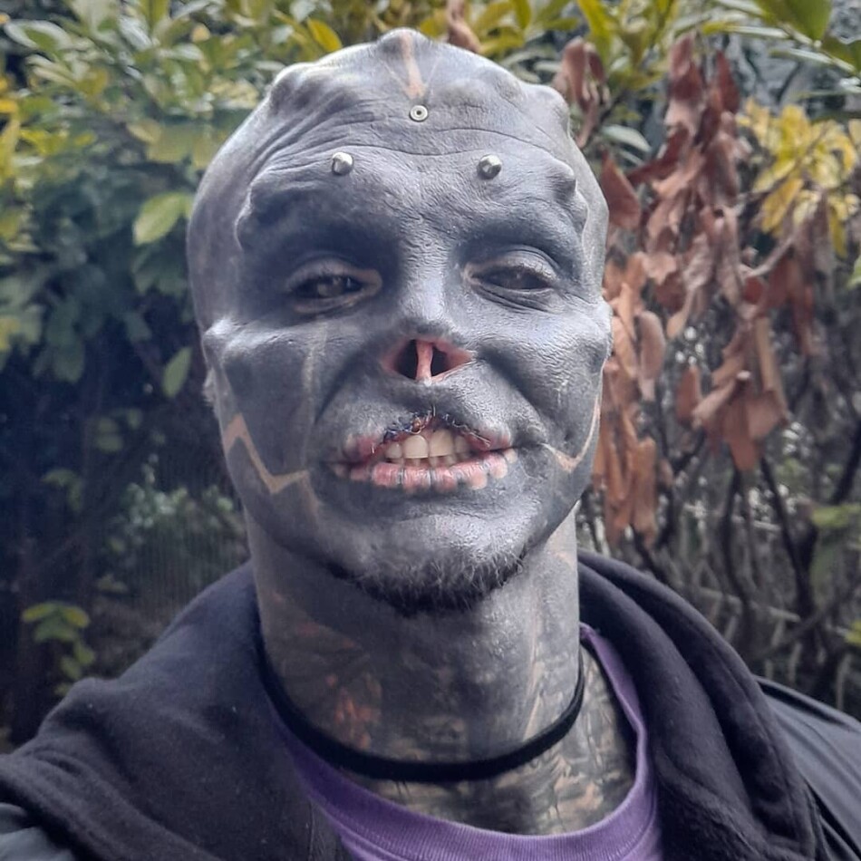 Anthony Loffredo tattoos: clean square portrait showing the forehead studs, facial blackout, white geometric cheek lines and neck tattoos
