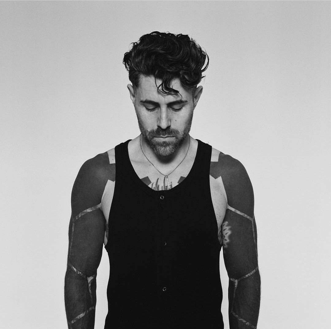 Davey Havok tattoos: studio portrait with both blacked-out arms visible and the shoulder-to-wrist coverage easy to study