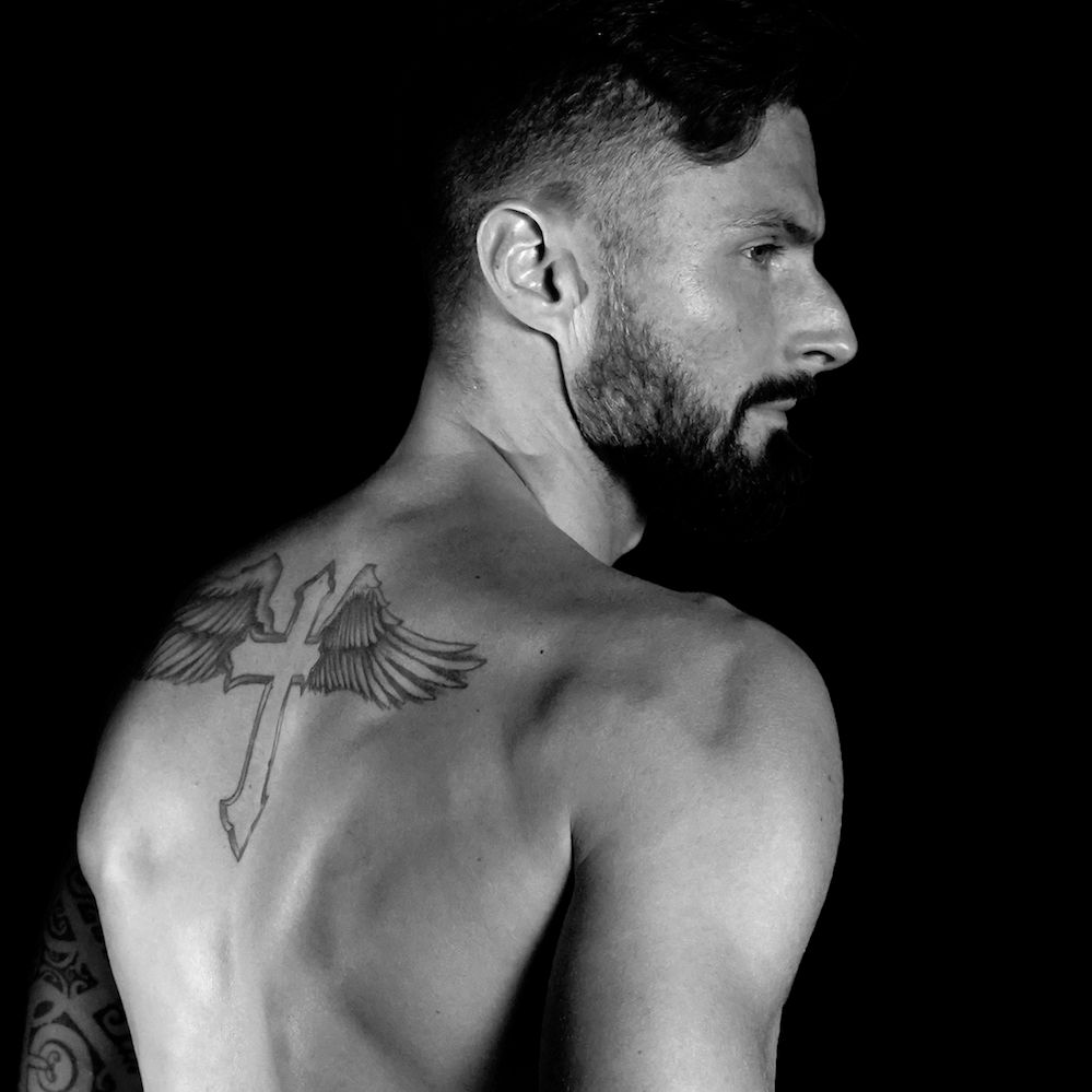 Olivier Giroud tattoos: Olivier Giroud shirtless back portrait showing the winged cross tattoo
