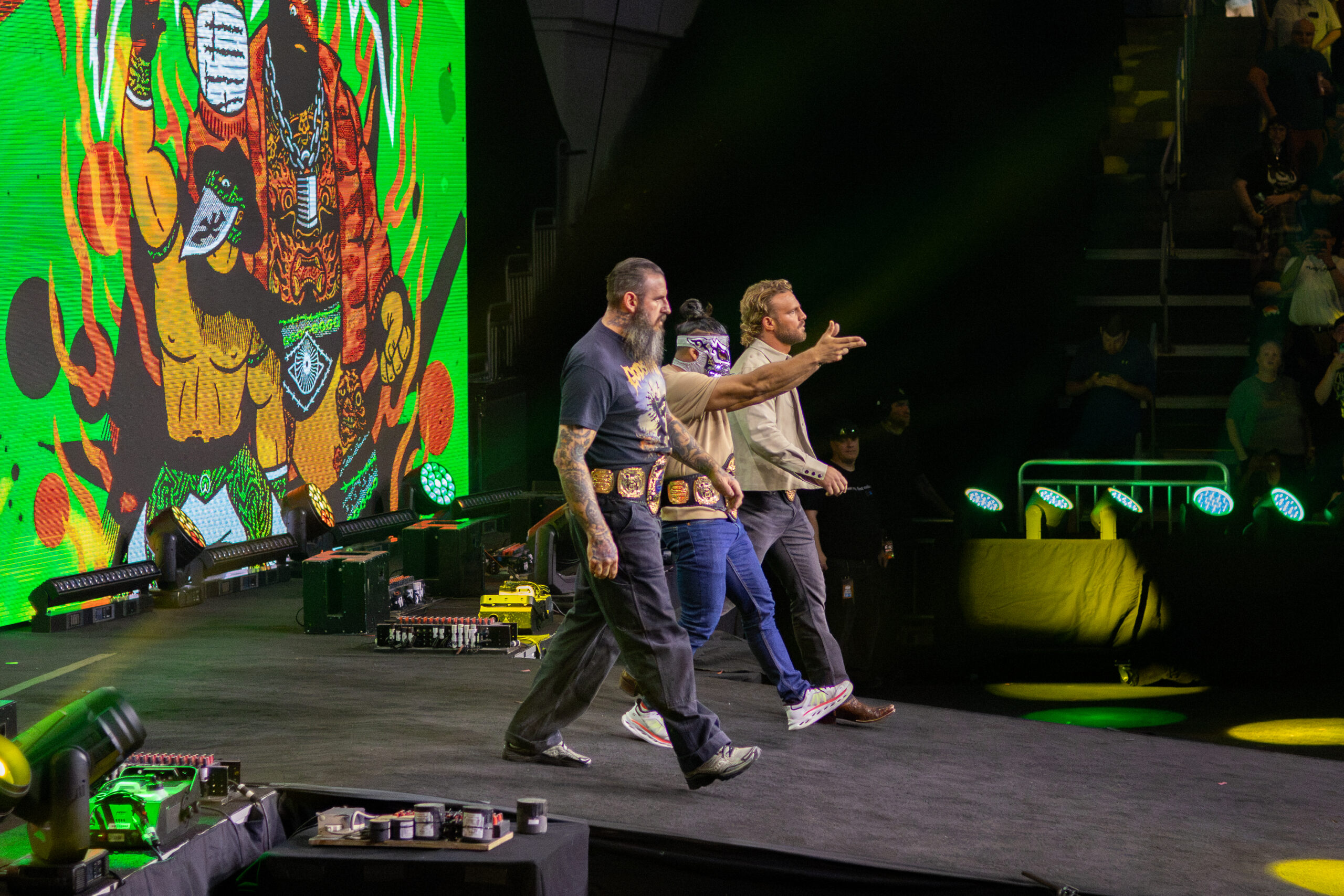 Brody King tattoos: high-resolution stage photograph showing the dense forearms and chest ink as King walks beside the ring