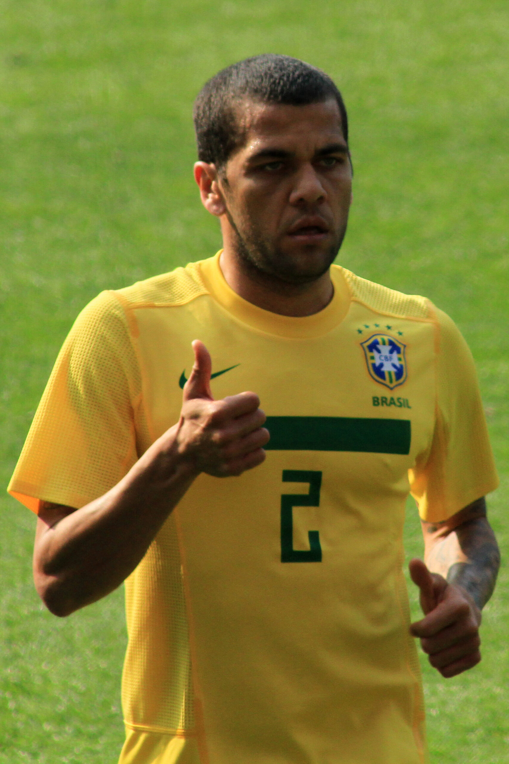 Dani Alves tattoos: clean high-resolution shirtless football photograph showing chest lettering, dates, the compass-like torso piece and both arms