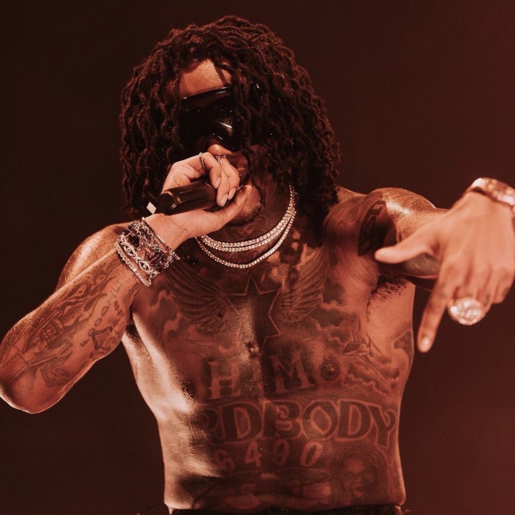 Gunna tattoos: black-and-white stage view of chest and arm tattoos