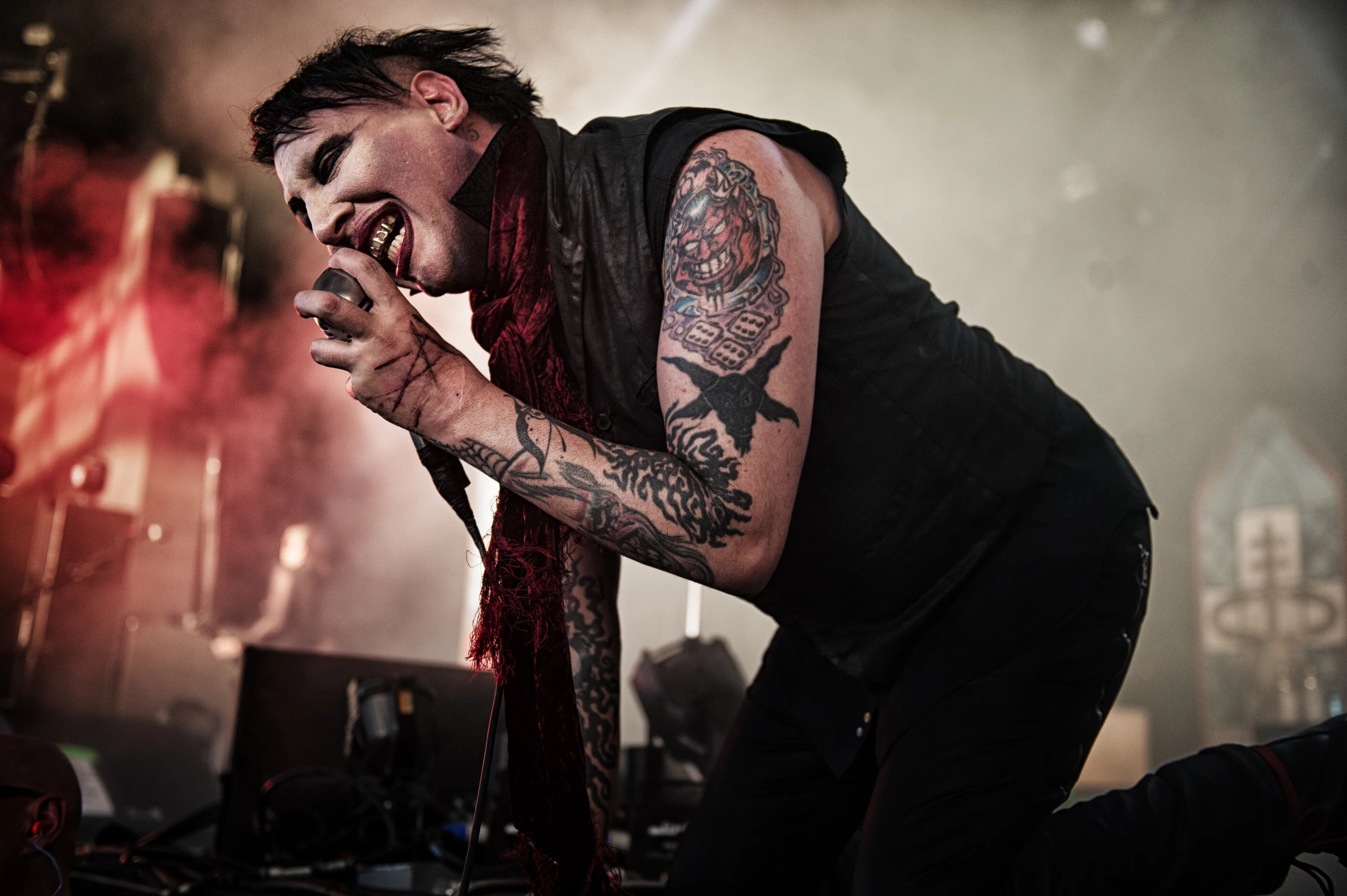 Marilyn Manson tattoos: wide live photograph with the tattooed forearms and upper-arm color visible beside the microphone