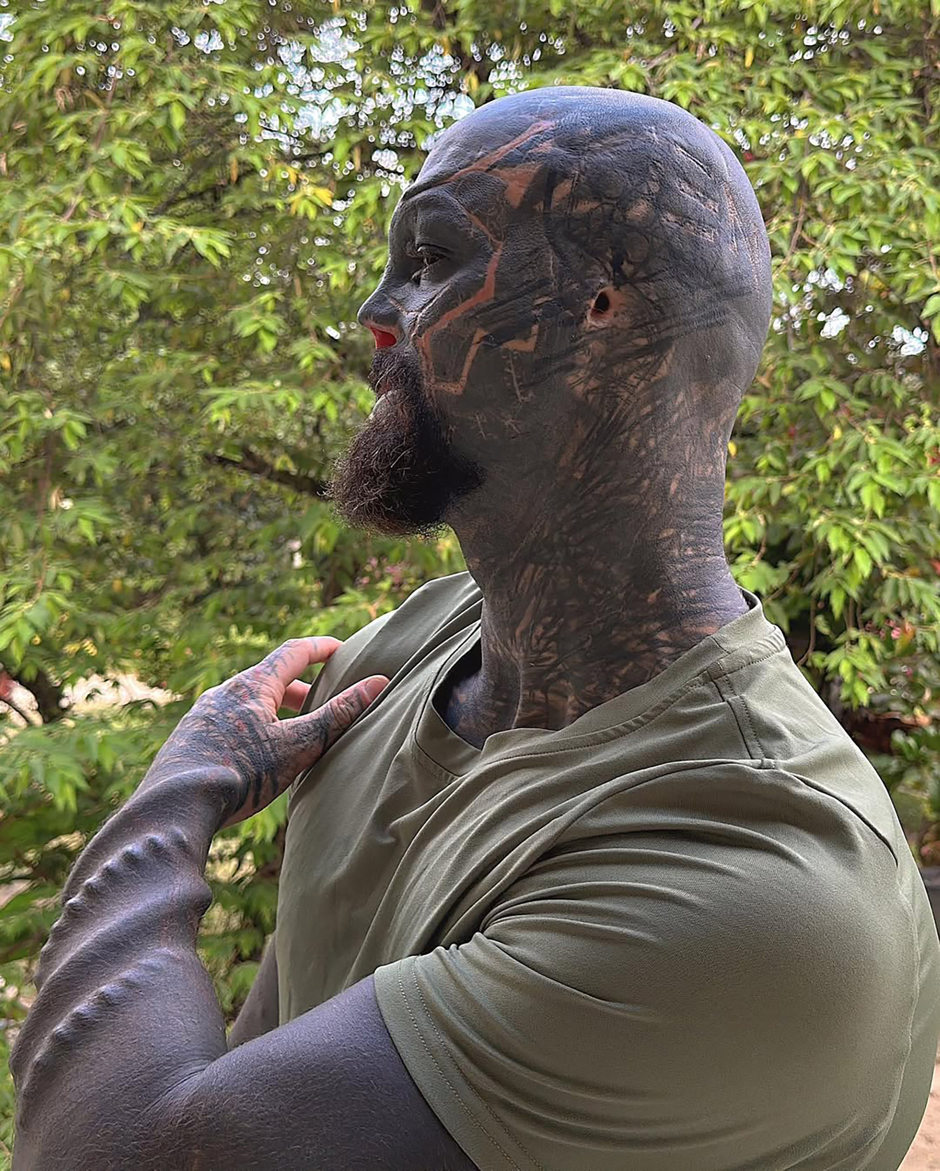 Anthony Loffredo tattoos: large side profile showing the head, neck and upper-arm tattoos with geometric pale lines across the dark fill