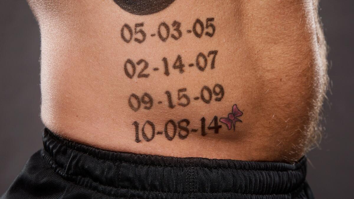 AJ Styles tattoos: inline close-up of black lettering and date spacing