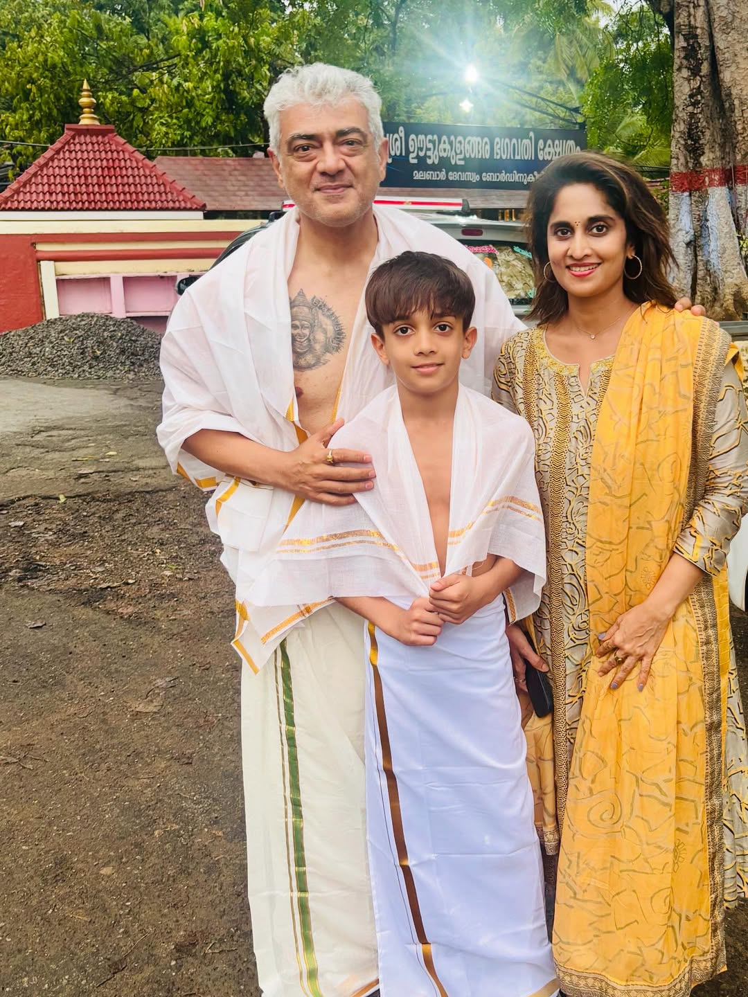 Ajith Kumar tattoos: full family temple portrait with the right chest tattoo visible beside Shalini and Aadvik