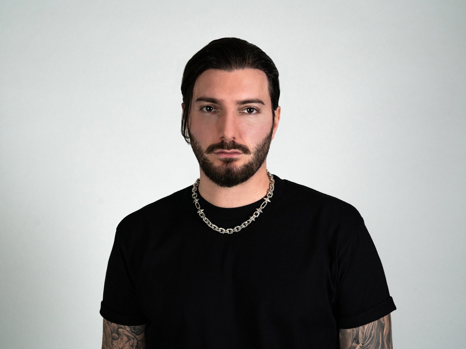 Alesso tattoos: both tattooed arms visible beneath a black shirt