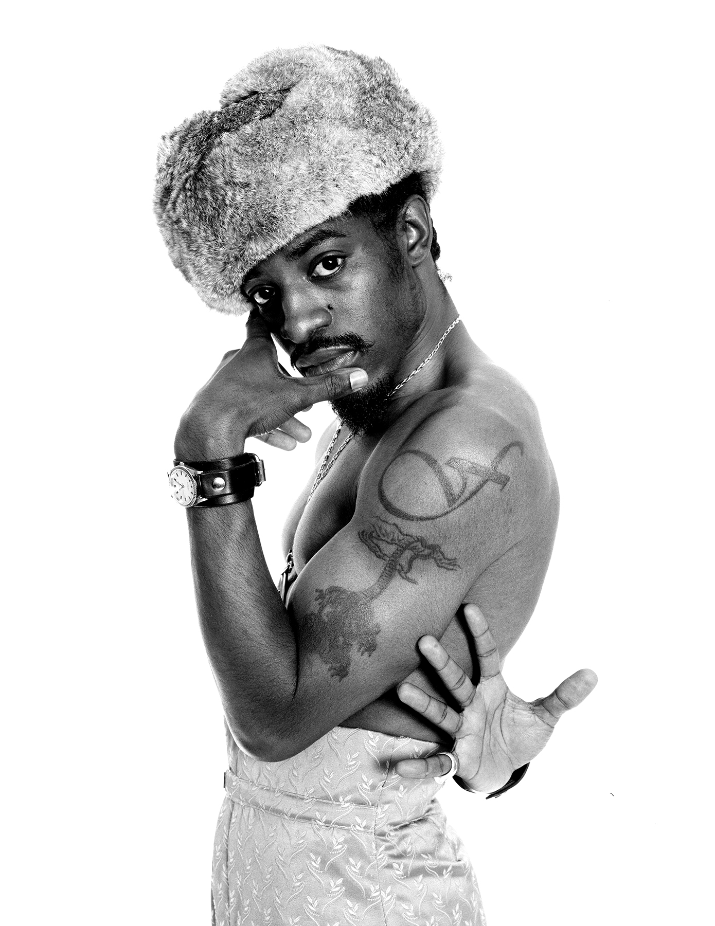 André 3000 tattoos: High-resolution Janette Beckman portrait showing the looping upper-arm symbol and dragon tattoo clearly.