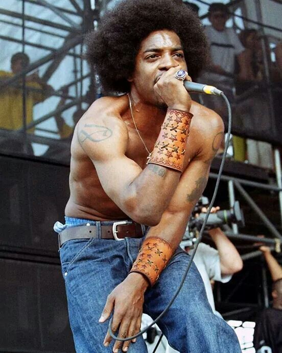André 3000 tattoos: Live-performance photograph showing André's shoulder, upper-arm and forearm tattoos while he performs shirtless.