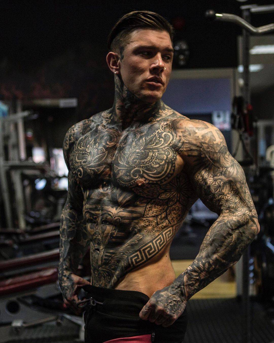 Andrew England tattoos: Left upper-arm geometric field, shaded forearm and sleeve transitions