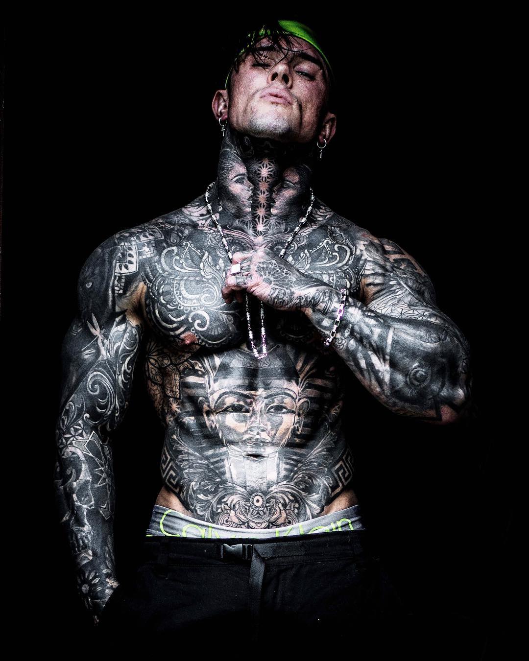 Andrew England tattoos: Two inward-facing neck portraits and central starburst strip