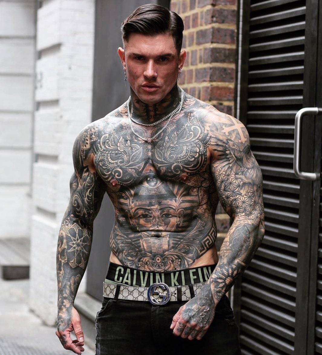 Andrew England tattoos: Paired curling ornamental panels covering both pectorals