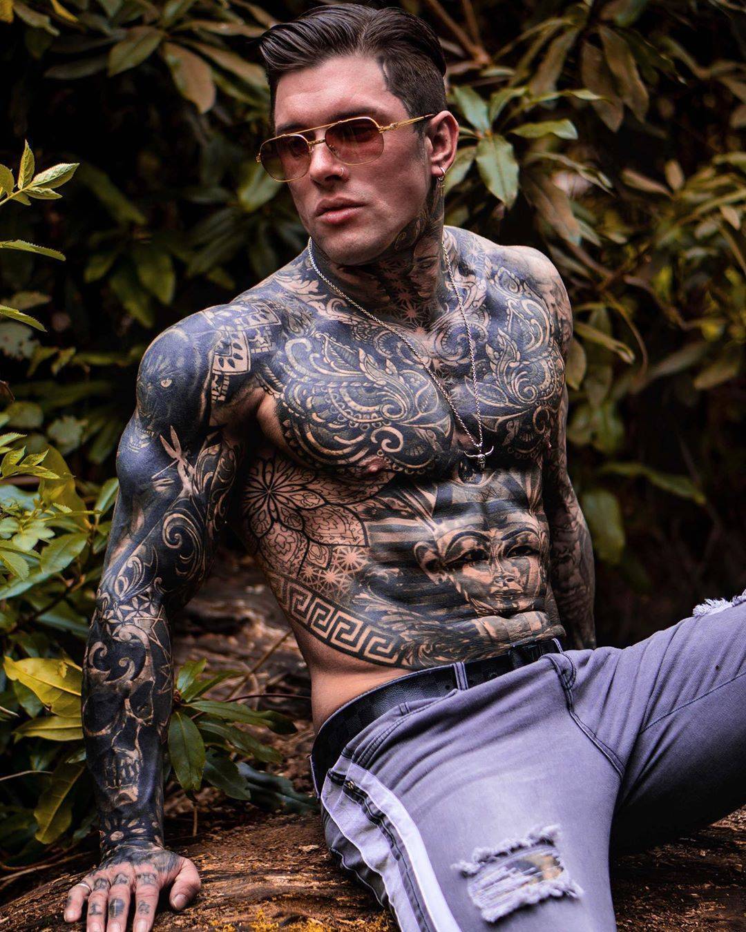 Andrew England tattoos: Large Egyptian-style pharaoh face, striped headdress and angular lower torso border